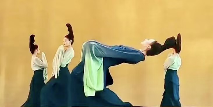 青绿舞者下腰，身体拱成山势轮廓